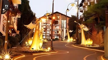 Uma rua com uma estrada sinuosa, postes de luz e um edifício com varandas.