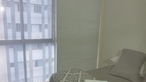 Een slaapkamer met een bed, een raam met zonwering en een betegelde vloer.