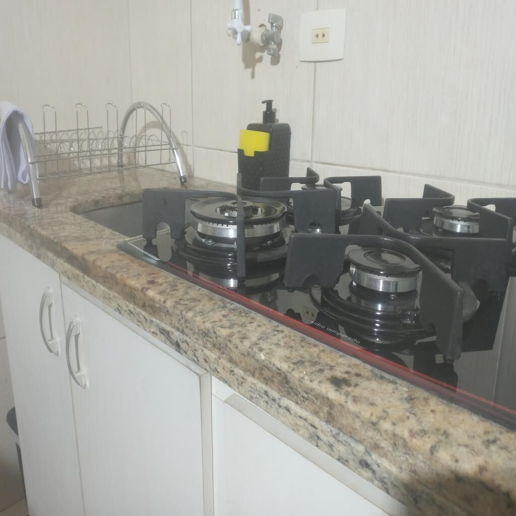 A kitchen with granite countertops, a gas stove, a sink, and a dish drying rack.
