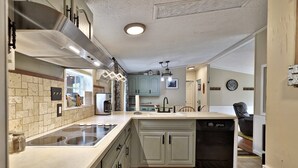 Une cuisine dotée d’un îlot central, d’une cuisinière intégrée et d’un lave-vaisselle.