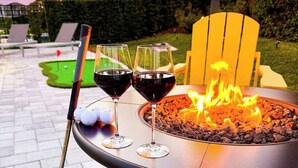 Un foyer extérieur avec deux verres de vin rouge et un club de golf.