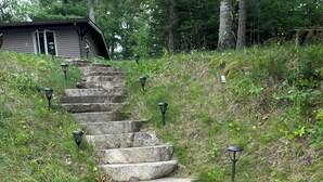 A stone staircase leading up a grassy hill with a house in the background. - Perfect Cabin on Pokegama Lake (Grand Rapids)