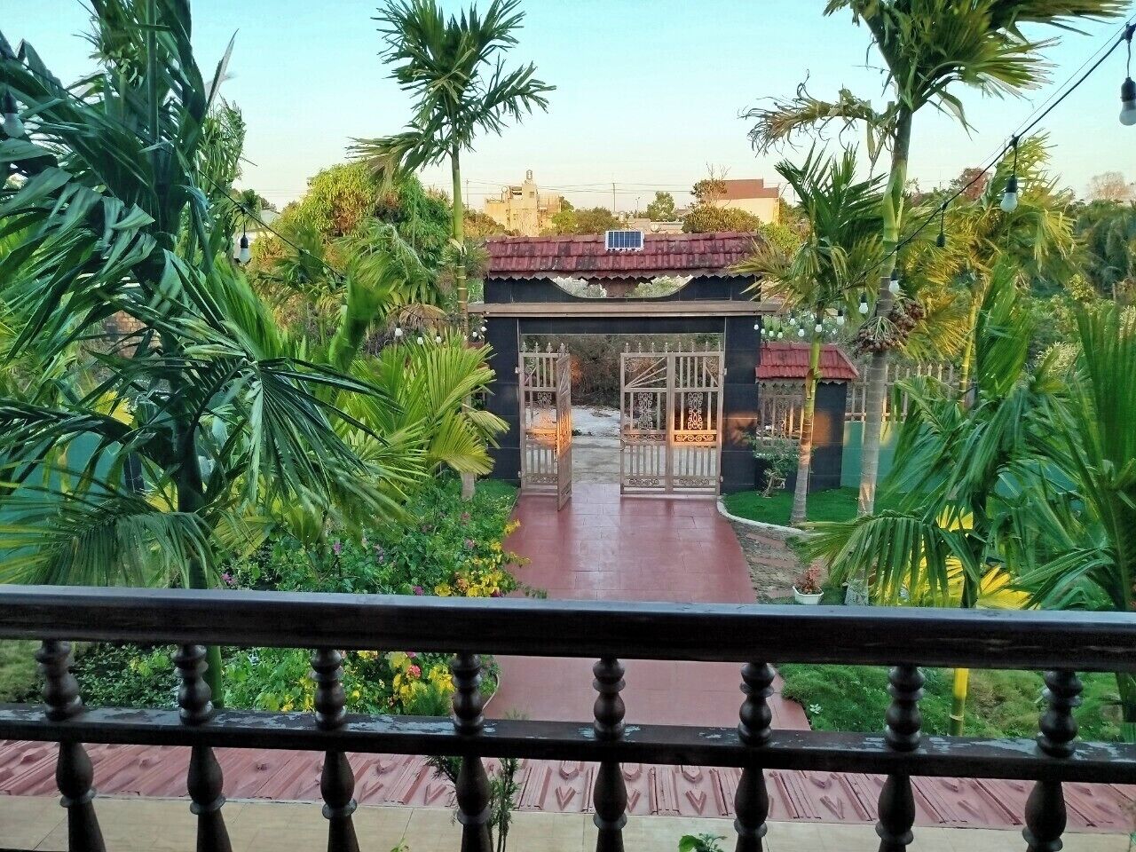 A view of a garden pathway leading to a building with a traditional design, surrounded by lush greenery.