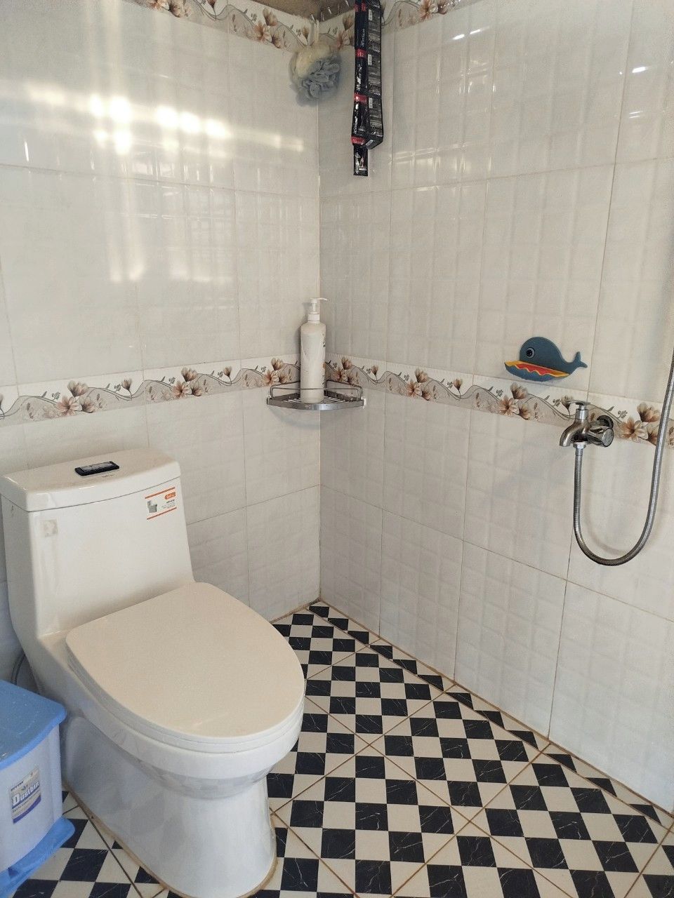 A bathroom with a toilet, a shower, and a checkered floor.