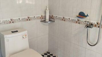 A bathroom with a toilet, a shower, and a checkered floor.