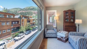A room with a large window overlooking a street and buildings, a wooden cabinet, a chair, and a sofa. - Amazing Top Floor Ghostrider (Telluride)