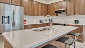Una cucina moderna con mobili in legno, frigorifero in acciaio inossidabile, forno a microonde e un'isola grande con lavello.