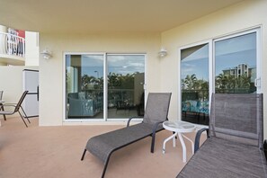A balcony with a chair, a small table, and a view of palm trees and buildings.