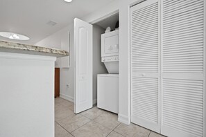 A laundry room with a washing machine, a dryer, and a closed closet. - Peace of Paradise: Pool & Palms View and Beach Access (Treasure Island)