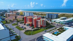 A coastal hotel with multiple buildings, a parking area, and a view of the beach. - Peace of Paradise: Pool & Palms View and Beach Access (Treasure Island)