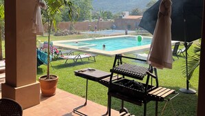 Un patio couvert avec un barbecue, une piscine et une vue sur les montagnes.