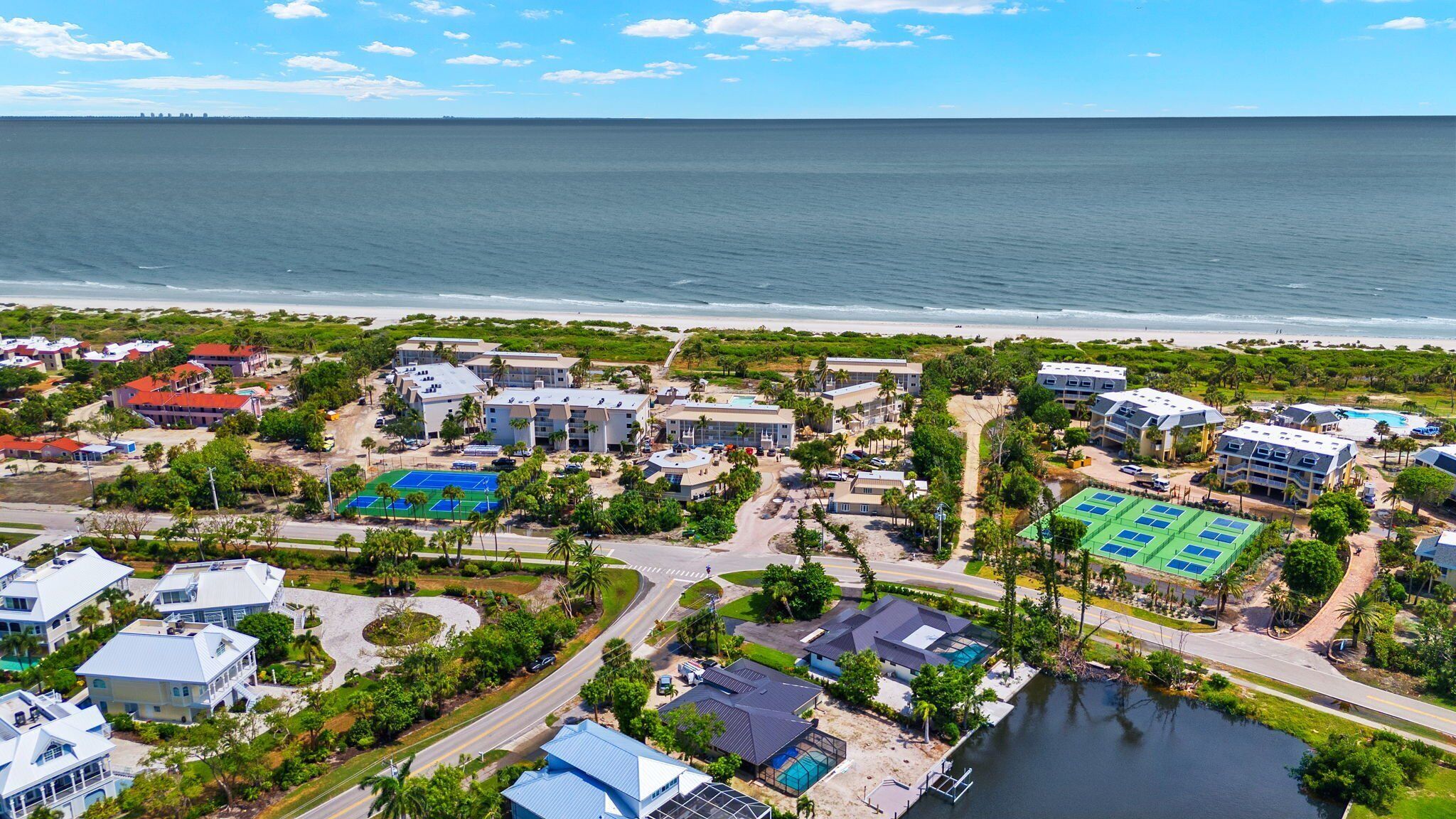An aerial view of a coastal resort with multiple buildings, a beach, and a marina.