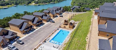 A residential area with a swimming pool, multiple houses, and a view of a lake.