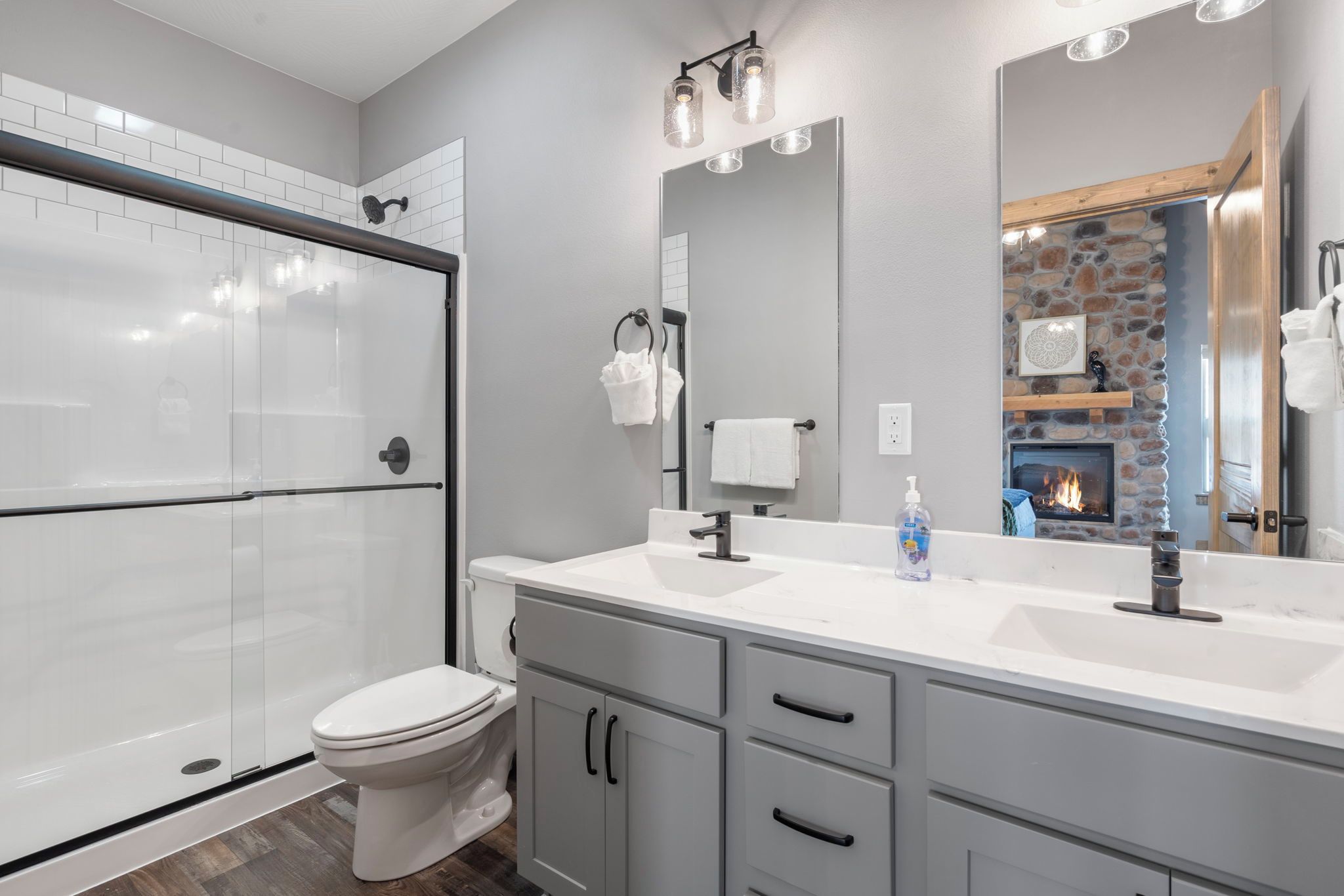 A modern bathroom with a glass shower enclosure, a toilet, a vanity with a sink, and a mirror.