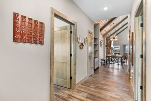 A hallway with wooden flooring, a dining area with a table and chairs, and a sign on the wall. - New Log Cabin with Ozark Views, Free Daily Local Attraction Tickets & Community Amenities (Branson)