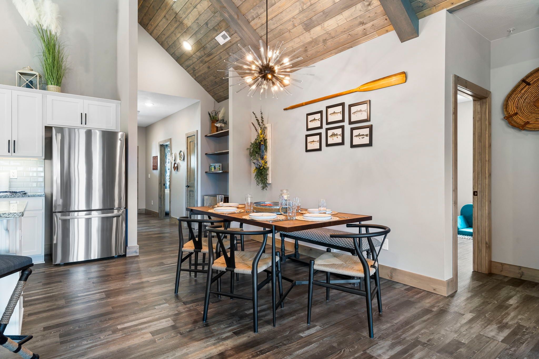 A modern kitchen with a stainless steel refrigerator, wooden dining table, and chairs.