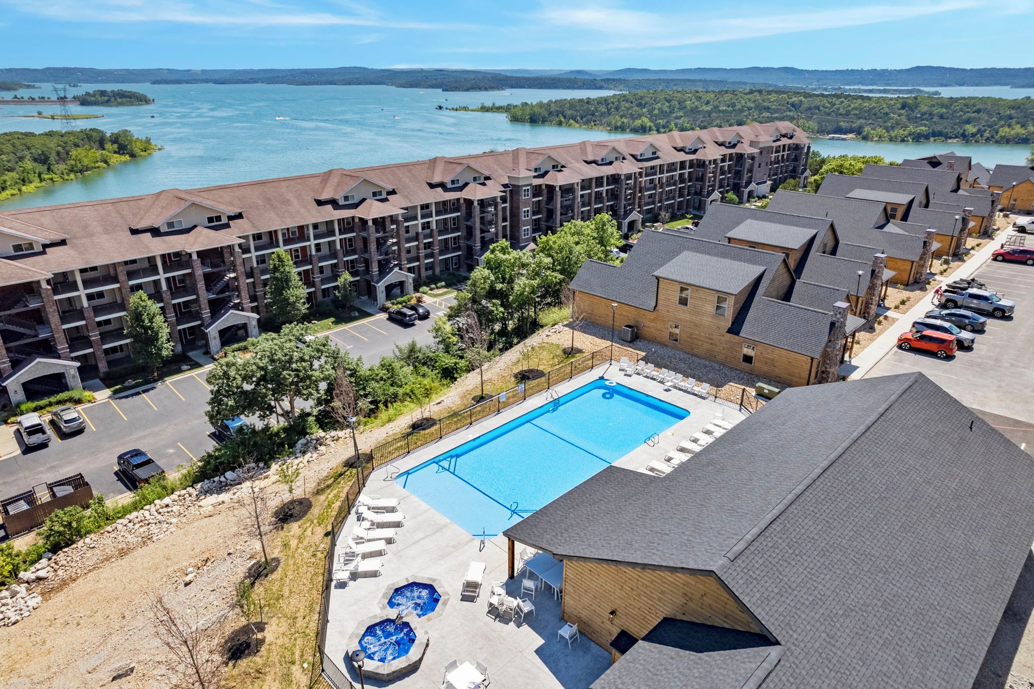 Et hotel med swimmingpool, udendørs siddepladser og udsigt til en sø.