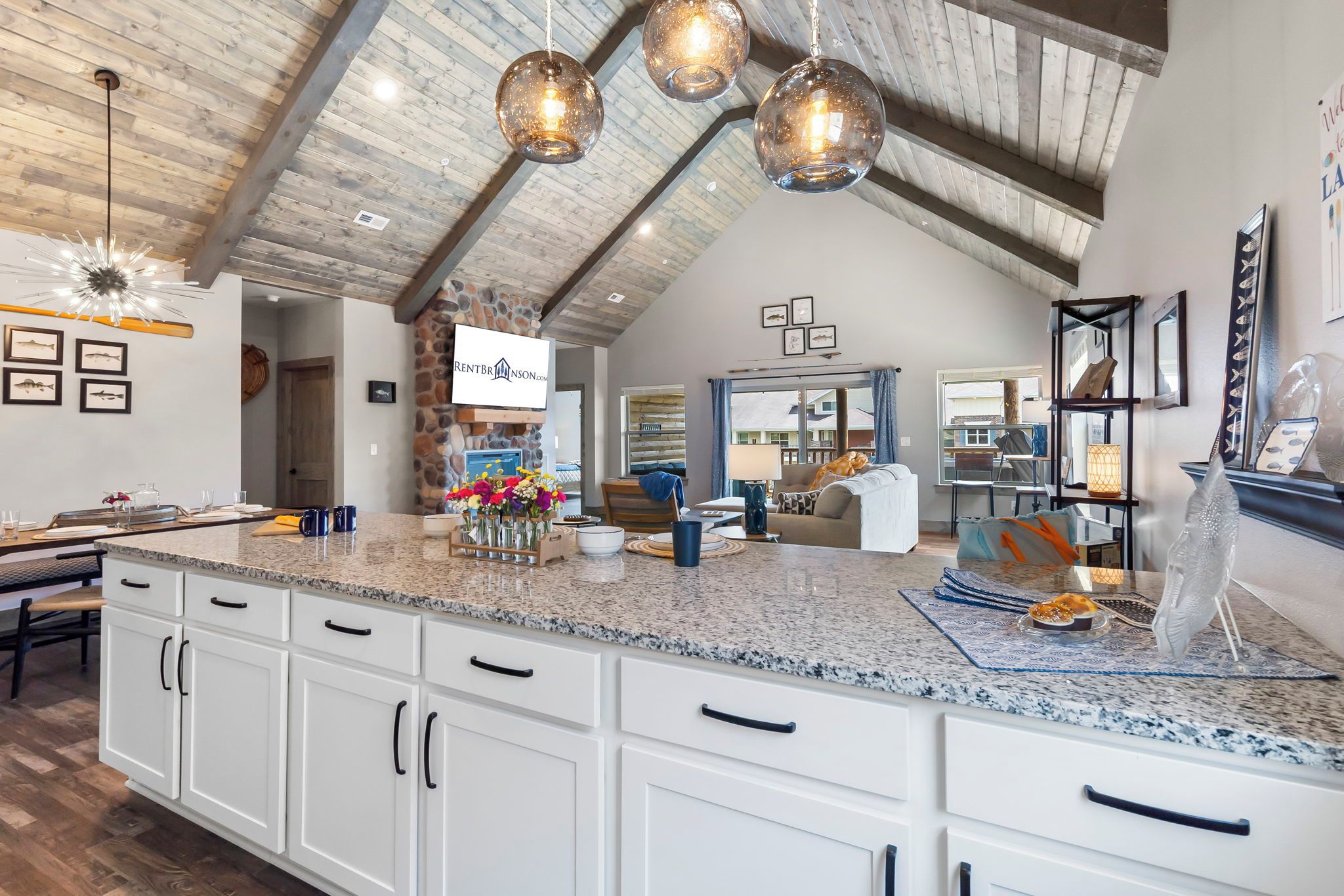 A spacious kitchen with granite countertops, white cabinetry, and a stone accent wall.