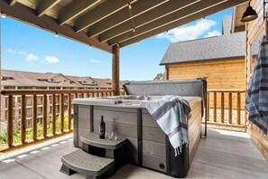 A hot tub on a wooden deck with a view of residential buildings. - New Log Cabin with Ozark Views, Free Daily Local Attraction Tickets & Community Amenities (Branson)