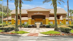 A hotel entrance with a sign reading "ENCANTADA CLUBHOUSE," surrounded by palm trees and well-maintained landscaping. - Encantada Resort: Pool, Gym, Clubhouse, 10min to Disney (Kissimmee)