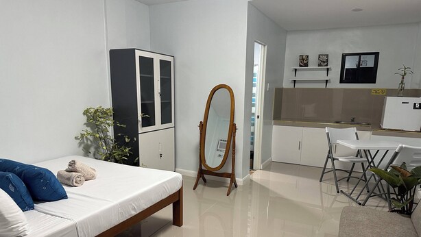 A modern bedroom with a bed, a wardrobe, a mirror, and a small kitchenette. - Room 805 @ Pennington Inn, Guimaras (Western Visayas)