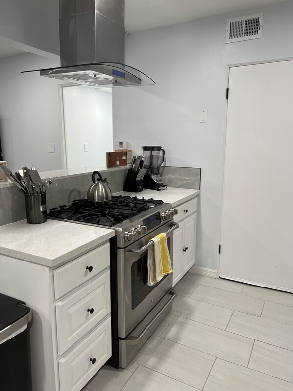 A modern kitchen with a gas stove, oven, and a coffee maker on the countertop.