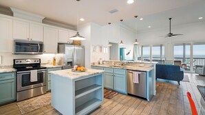 A modern kitchen with stainless steel appliances, a large island, and a view to the outside.