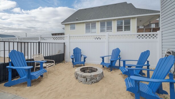 A backyard with a fire pit, blue Adirondack chairs, and a white fence. - 4770 - I'm Free - Semi-Oceanfront Oasis w/ Pool & Hot Tub (Kitty Hawk)
