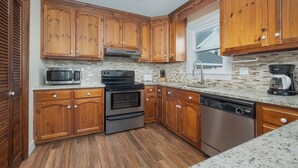 A kitchen with wooden cabinets, a microwave, stove, dishwasher, and granite countertops. - 4770 - I'm Free - Semi-Oceanfront Oasis w/ Pool & Hot Tub (Kitty Hawk)