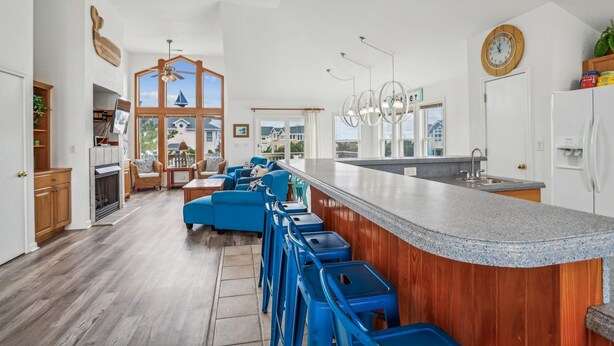 A spacious kitchen with a large island, bar stools, and a view of the outside. - 1620 - Triple 7 - Corolla Sleeps 20 | Pool, Hot Tub & Beach Walk (Corolla)