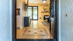 A spacious entrance with a tiled floor, a welcome mat, and a view into a well-lit interior with a kitchen area visible. - New! Private Oasis W Pool, Outdoor BBQ & Gameroom!! (Indio)
