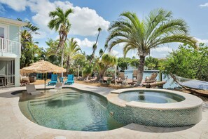 A pool area with lounge chairs, a hot tub, and a thatched-roof structure. - Rest A Shore Waterfront Home, Brand New Private Pool (Marathon)