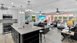 A modern kitchen with stainless steel appliances, a large island with a sink, and pendant lighting.