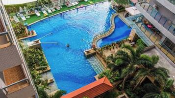 Una piscina de borde curvo, rodeada de sillas de descanso y palmeras.