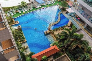 Ein Pool mit gewölbter Kante, umgeben von Liegestühlen und Palmen.