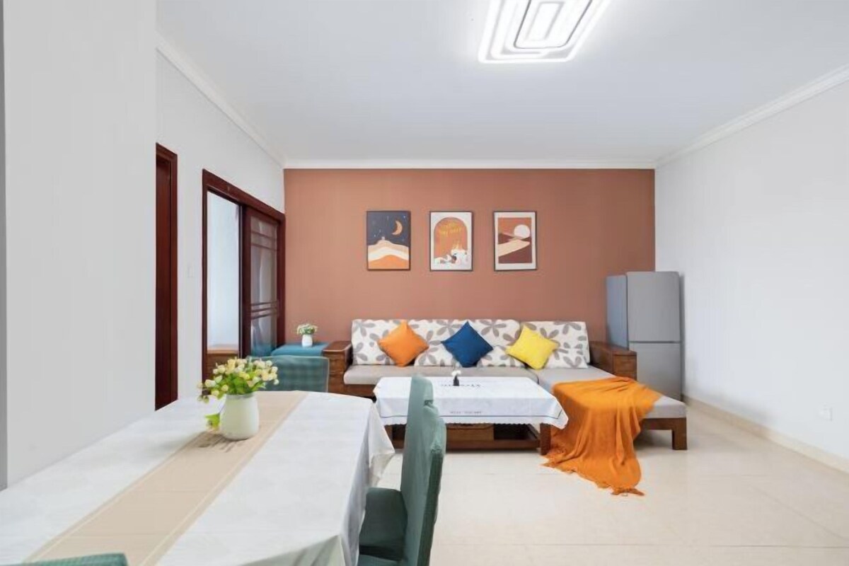 A modern living room with a sofa, a dining table, and a TV.