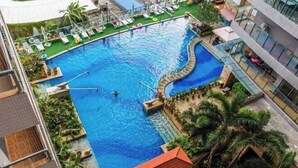 A large outdoor swimming pool with lounge chairs and a small waterfall feature. - Sanya Seaside Breeze Homestay (Sanya)