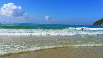 A beach with clear water, a sandy shore, and a distant coastline.