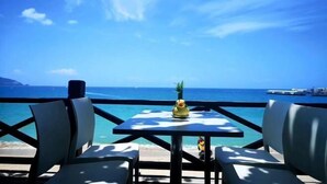 A table with a pineapple centerpiece, overlooking a beach with clear blue water and a distant view of boats. - Sanya Seaside Breeze Homestay (Sanya)