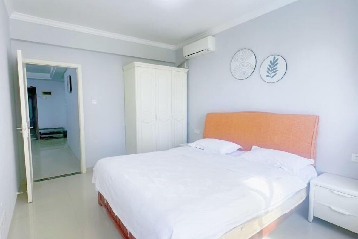 A bedroom with a bed, white wardrobe, and a nightstand.