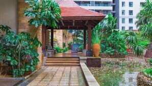 A covered outdoor area with steps leading to a building entrance, surrounded by lush greenery and a small water feature. - Sanya Seaside Breeze Homestay (Sanya)
