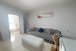A modern living room with a checkered sofa, a glass coffee table, and a minimalist design. - Sanya Seaside Breeze Homestay (Sanya)