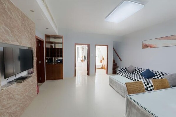 A modern living room with a flat-screen TV, a sofa with patterned cushions, and a large window. - Sanya Seaside Breeze Homestay (Sanya)