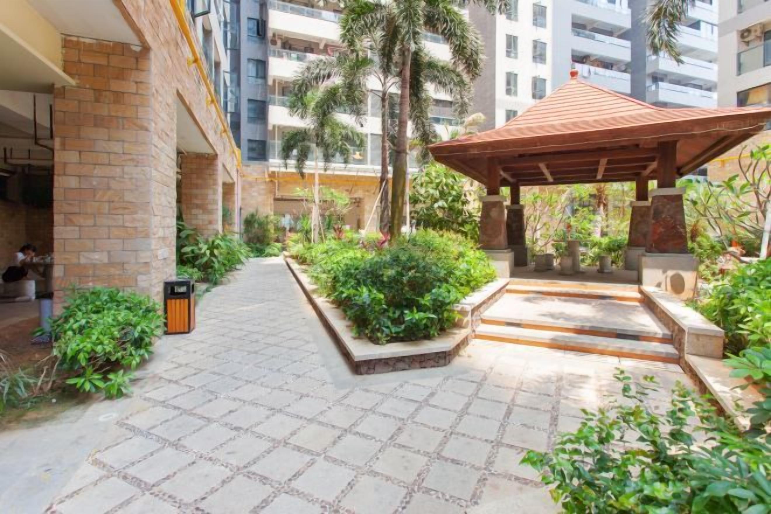 A courtyard with a tiled floor, a wooden pergola, and a variety of plants.