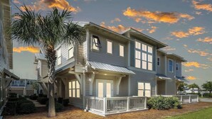 A two-story residential building with a balcony, a porch, and a small garden area.