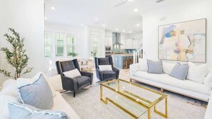 A modern living room with a sofa, two armchairs, a coffee table, and a ceiling fan.