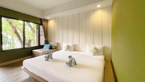 A hotel room with a large bed, a small seating area, and a window with a view of trees. - Samed Hideaway Resort (Koh Samet)