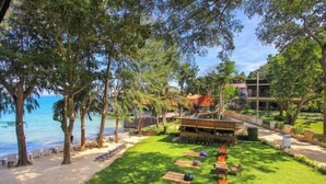 A beachside resort with a grassy lawn, wooden lounge chairs, and a barbecue area. - Samed Hideaway Resort (Koh Samet)