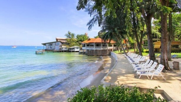 A beachfront property with a row of white lounge chairs, a wooden deck, and a view of the ocean. - Samed Hideaway Resort (Koh Samet)