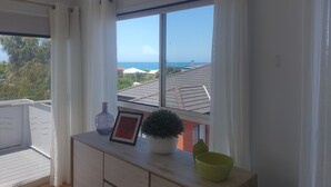 A balcony with a view of the sea, a potted plant, a framed picture, and a vase. - 11A Seaview. 
Ocean and Otway Ranges views. Close to beach. Pet friendly. (Apollo Bay)